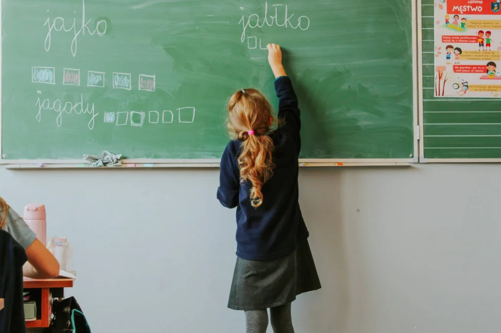 dziewczynka w szkole pisze na tablicy